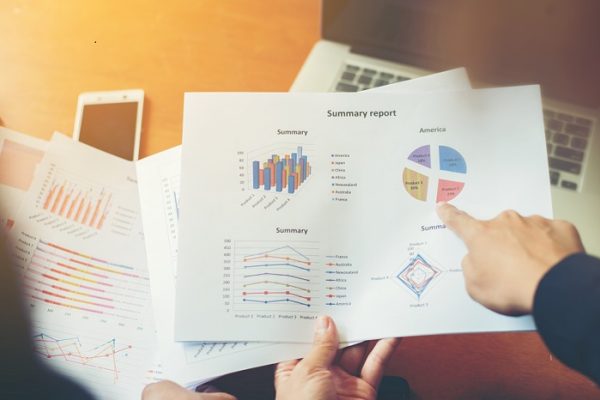 Team Business professionals working together at office wooden desk, hands close up pointing out financial data on a report.